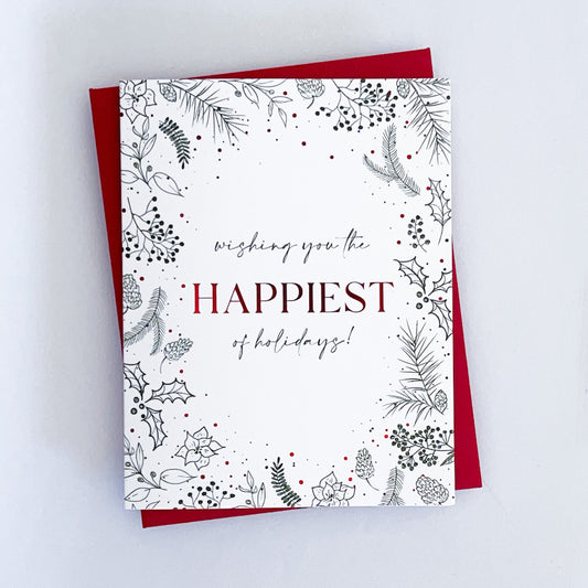 A holiday card with a white background featuring red foil accents and green holiday-themed illustrations, with the text 'Wishing you the happiest of holidays!' and 'Sending you joy & love' inside.