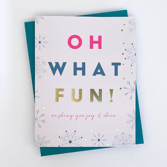 A holiday card with 'Oh what fun!' 'wishing you joy and cheer' printed  on a white background with gold foil accents, and a teal envelope.