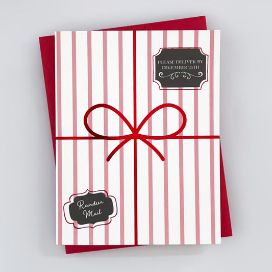 A holiday greeting card with a 'Please deliver by December 25th' 'reindeer mail' message, featuring red and white stripes and a red foil bow like a present. 