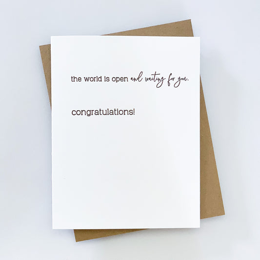 A letterpress congratulations card on a white background with black text that reads 'the world is open and waiting for you.' 'congratulations!' 