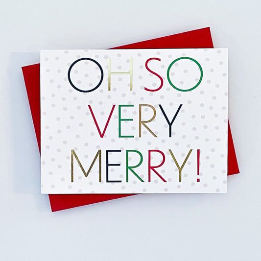 A holiday card with a white background  and light polka dots and red envelope. The card features the text 'Oh So Very Merry!' in colorful foil letters!'