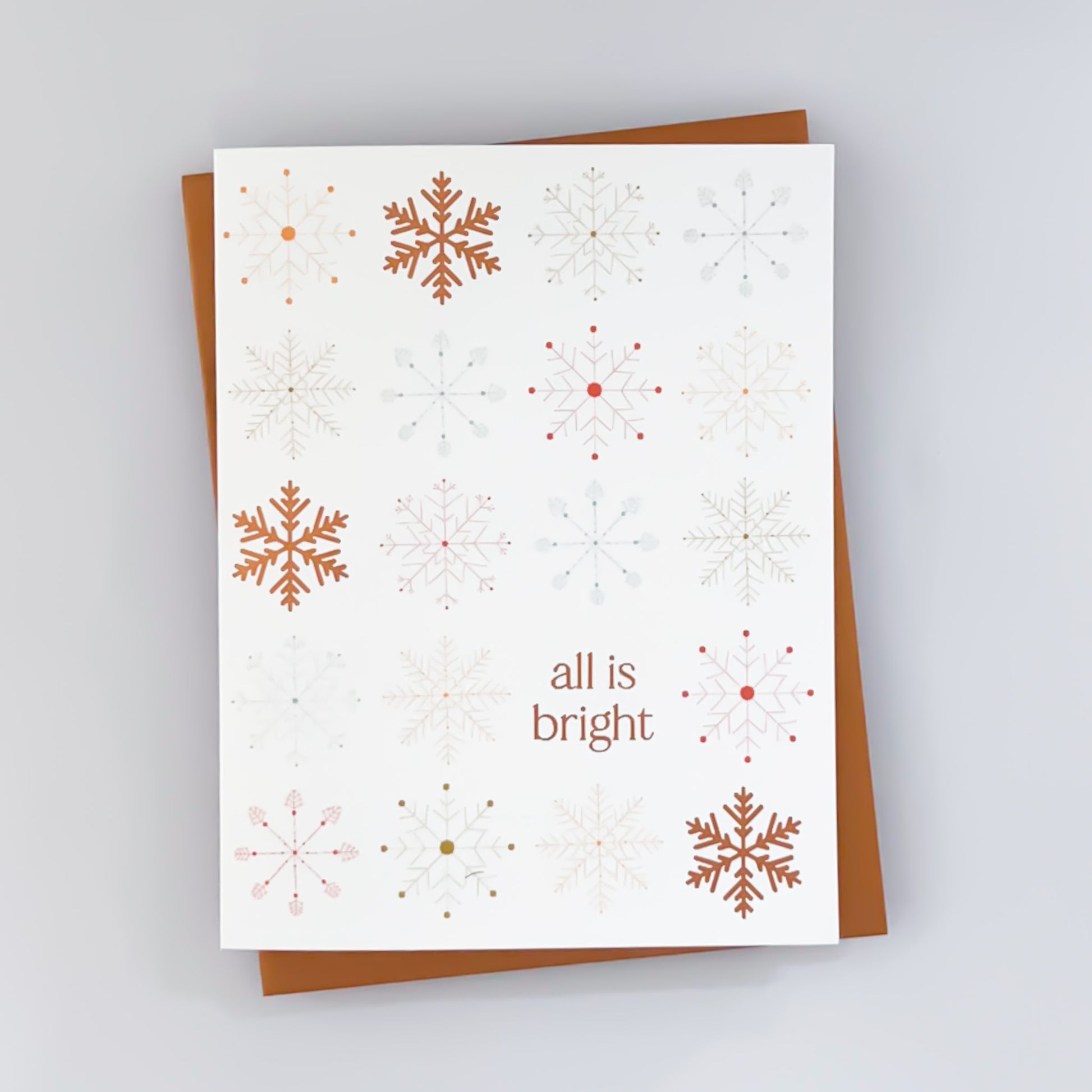 A holiday card with a white background featuring rust color snowflake patterns with the text 'All is bright'.