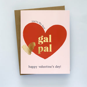 A valentines card with a pink background, featuring a red heart and the words 'you're the best' in a playful font, along with 'Gal Pal' and 'Happy Valentine's Day!' The card has gold foil accents and is shown with a kraft envelope.