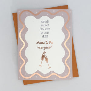 A Happy New Year Card with a wavy rose gold boarder featuring champaign flutes. The text reads 'Salud! Sante! Cin Cin! Prost! Skal! Cheers to the New Year!'.
