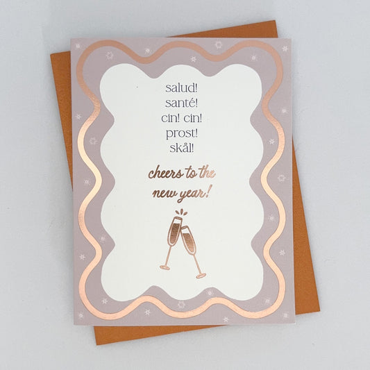 A Happy New Year Card with a wavy rose gold boarder featuring champaign flutes. The text reads 'Salud! Sante! Cin Cin! Prost! Skal! Cheers to the New Year!'.
