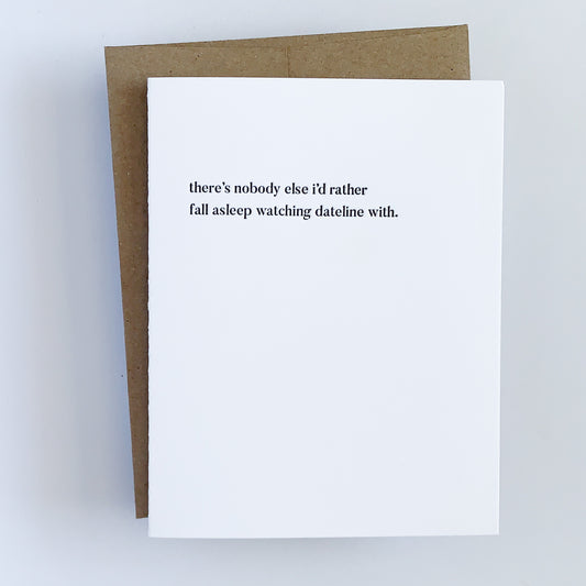 A letterpress card with white background and black text that reads 'there's nobody else i'd rather fall asleep watching dateline with'.