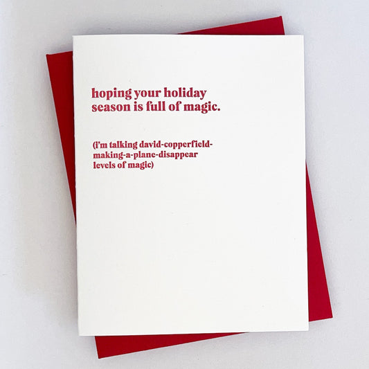 A letterpress holiday card with red text on a white background that reads "Hoping your holiday season is full of magic. (I'm talking david - copperfeild- making -a -plane - disappear levels of magic)'.