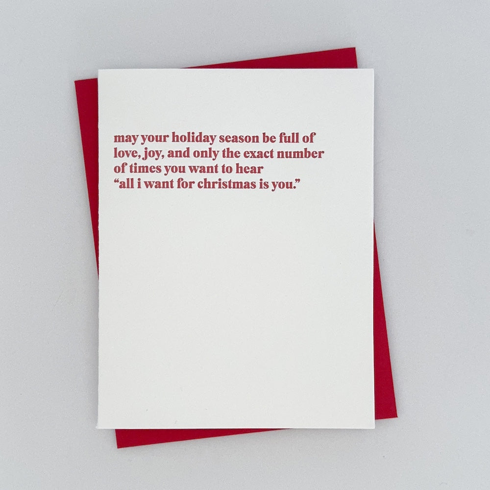 Letterpress Card that reads 'May your holiday season be full of love, joy, and only the exact number of times you want to hear "all i want for christmas is you' in red.