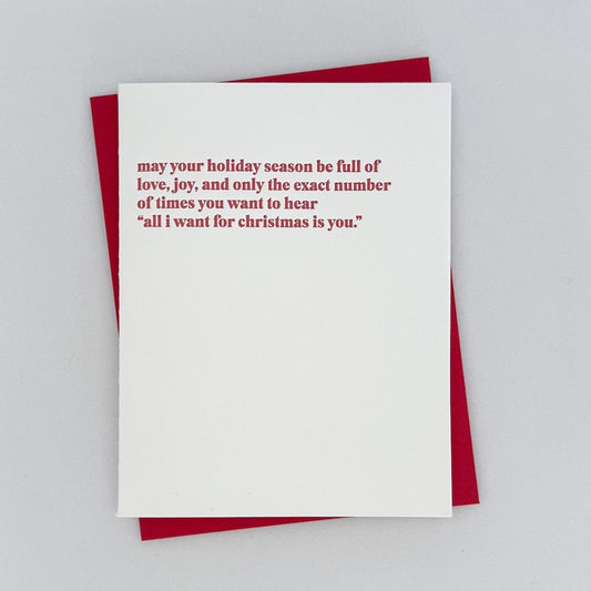 Letterpress Card that reads 'May your holiday season be full of love, joy, and only the exact number of times you want to hear "all i want for christmas is you' in red.