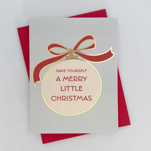 A holiday card that reads 'Have Yourself A Merry Little Christmas', featuring a red bow and a gold foil ornament design on a white background. The card is displayed with a red envelope behind it.